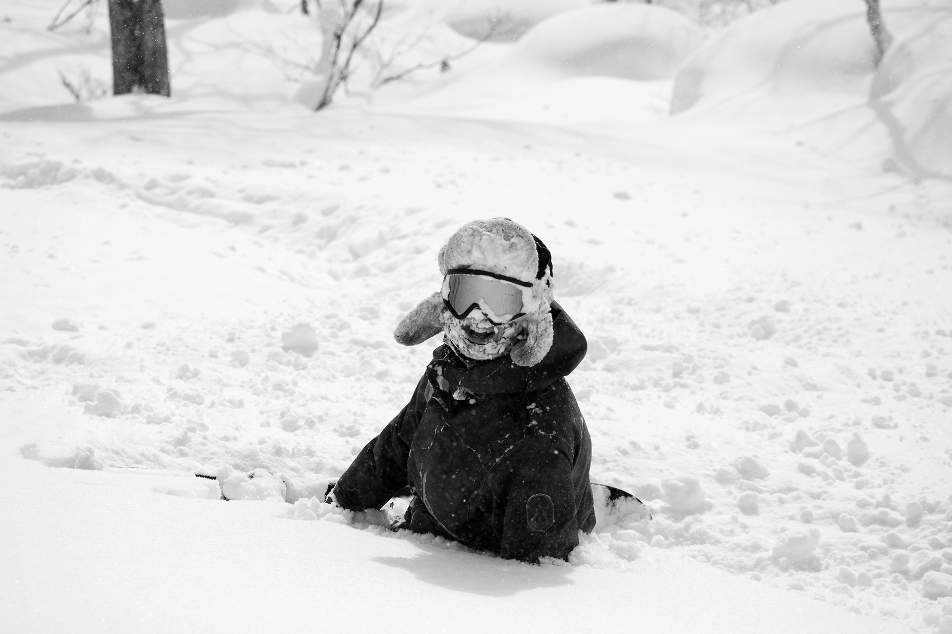A rider buried to the chest in powder, grinning