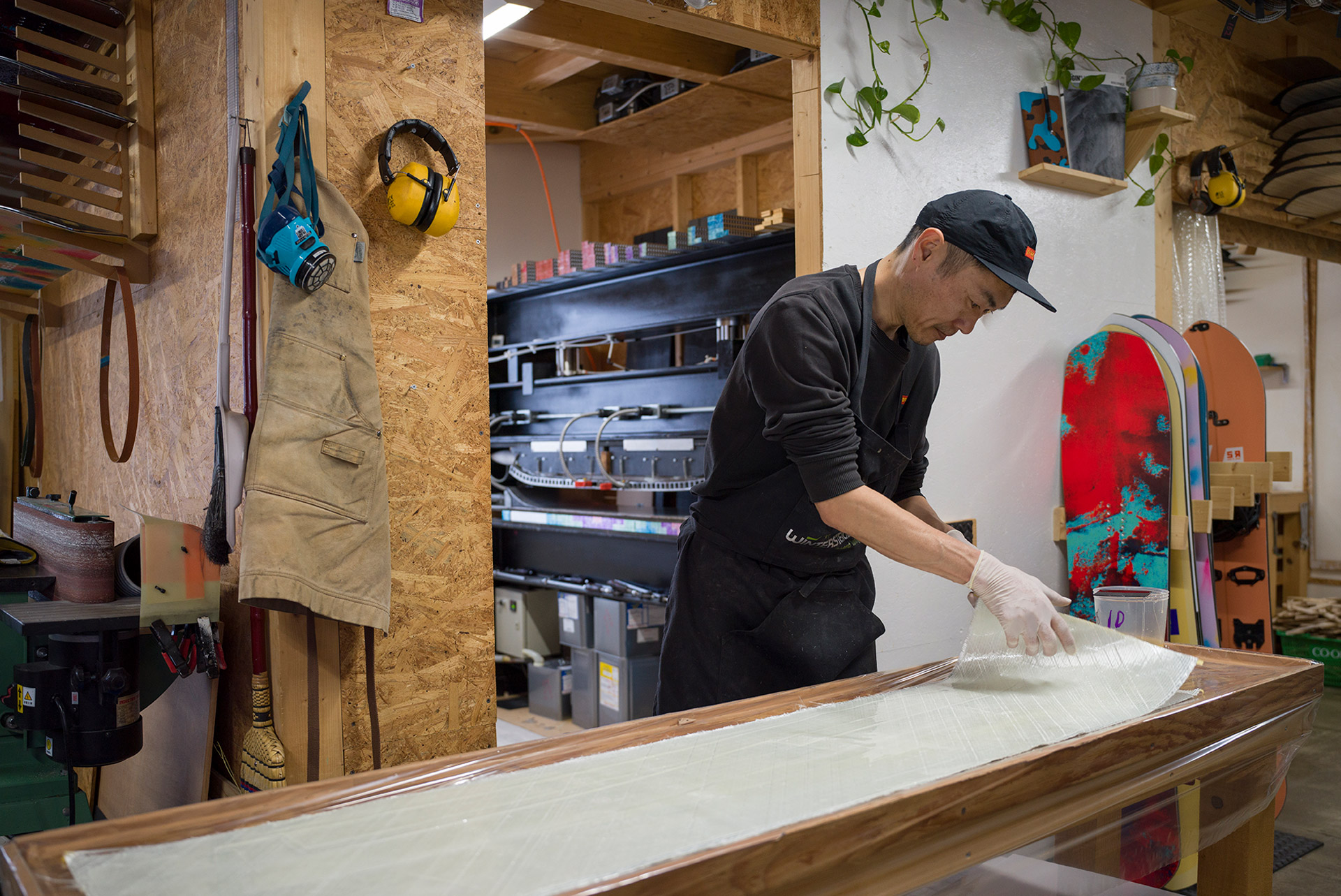 Pulling a sheet of fiberglass across the bench, the press waiting behind