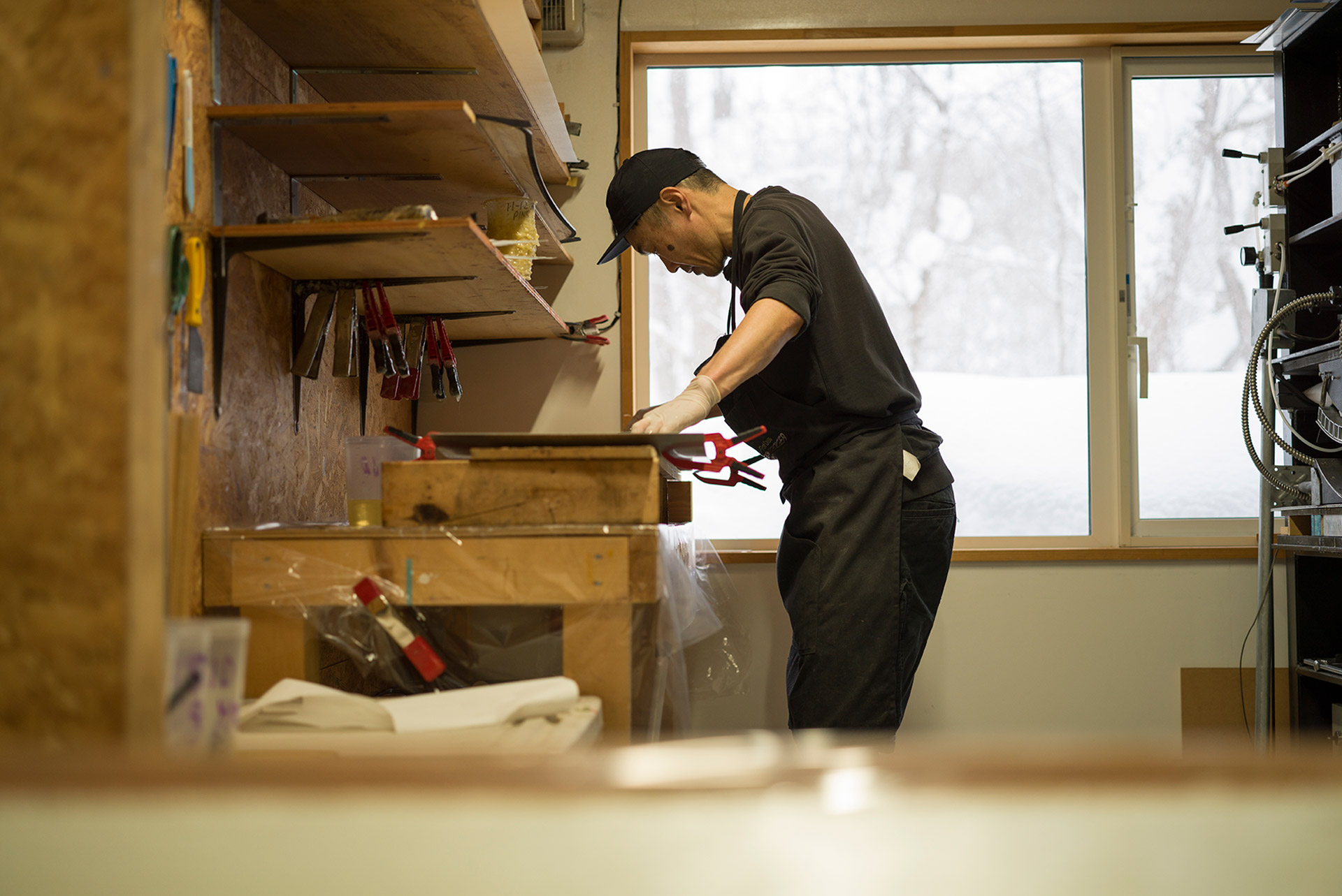 Tomohito Yamazaki at the bench in the Offshore workshop, winter outside